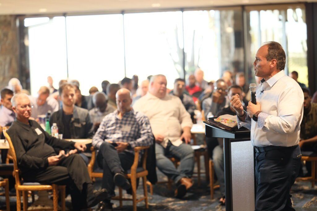 Speaker addresses seated audience in a bright conference room during a presentation