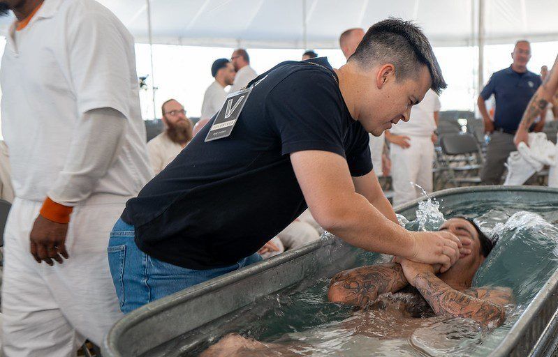 Man washing a person’s feet in a large basin during a ceremonial gathering