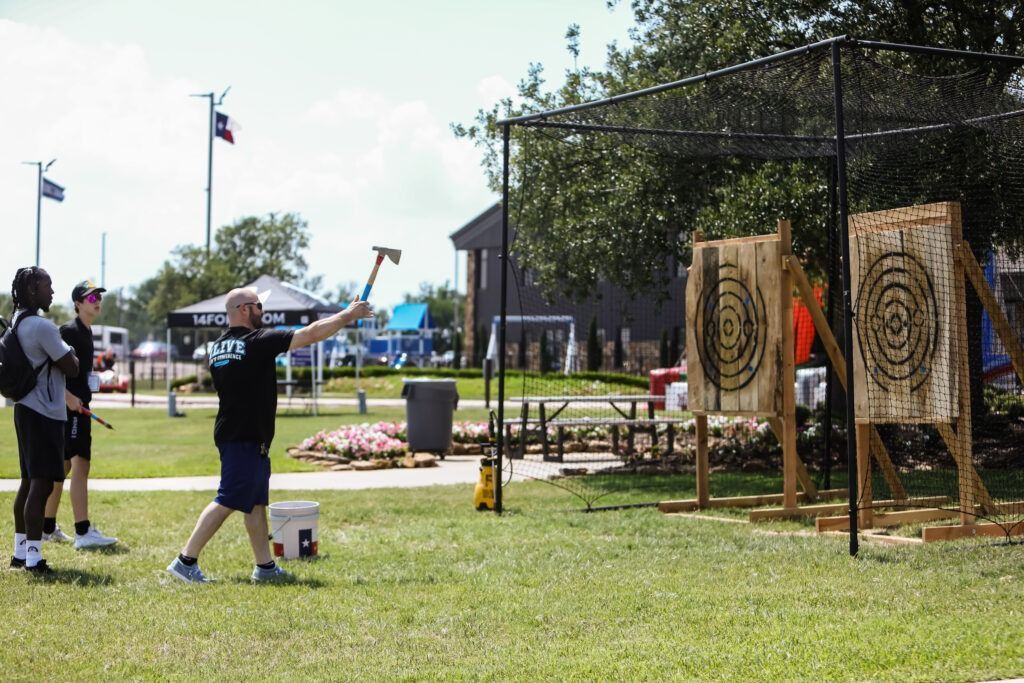 Two people throwing at archery targets outdoors on a grassy field