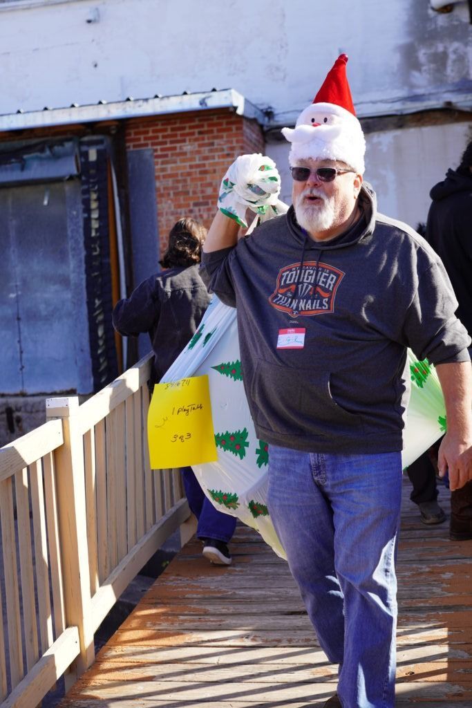 Man in Santa hat carrying a shopping bag on a wooden walkway outdoors