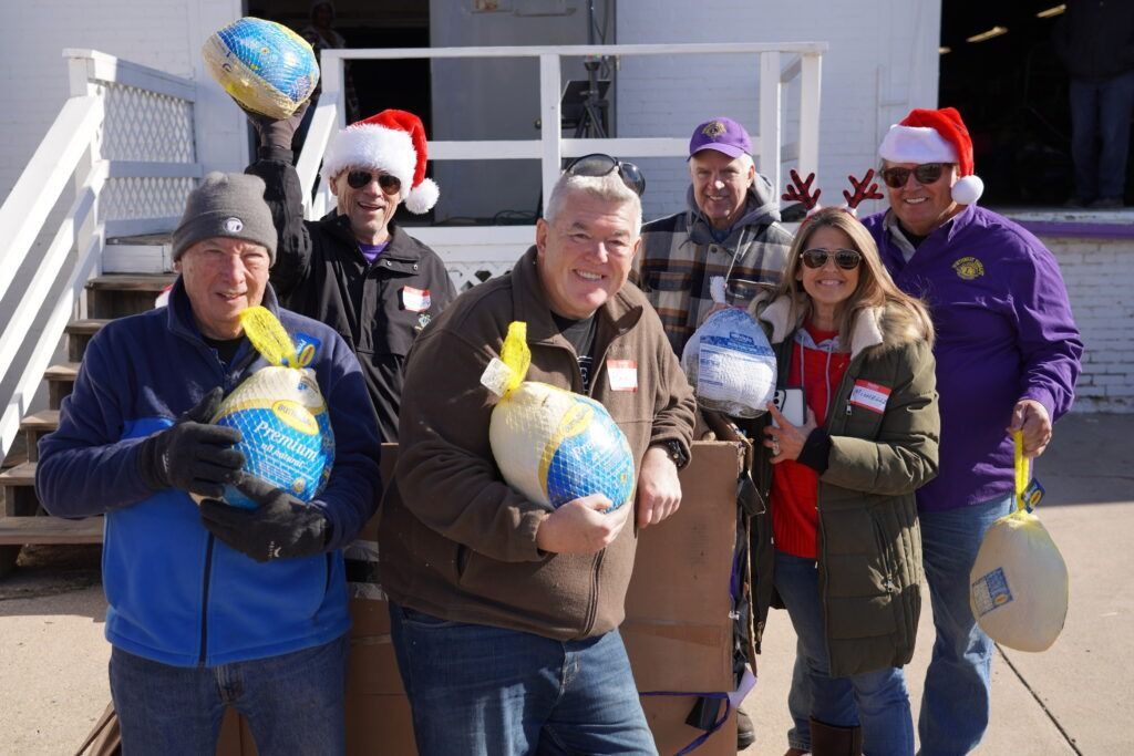 Group of people in winter clothes holding inflatable globes outdoors, some wearing Santa hats.