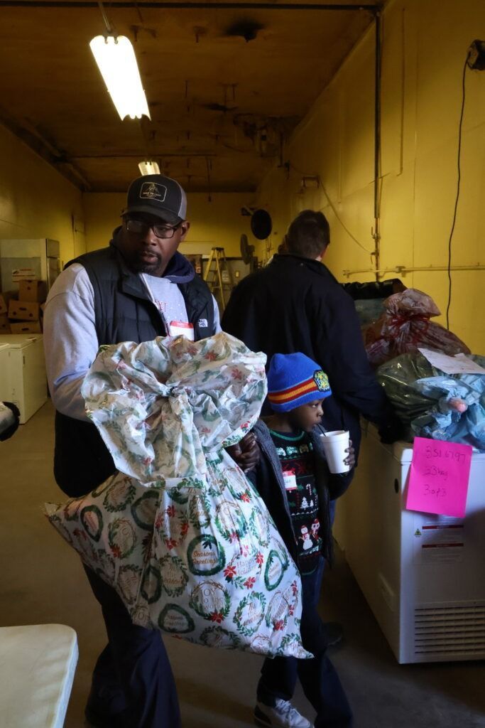 People inside a dim warehouse sorting large bags and bundled items under fluorescent lights.