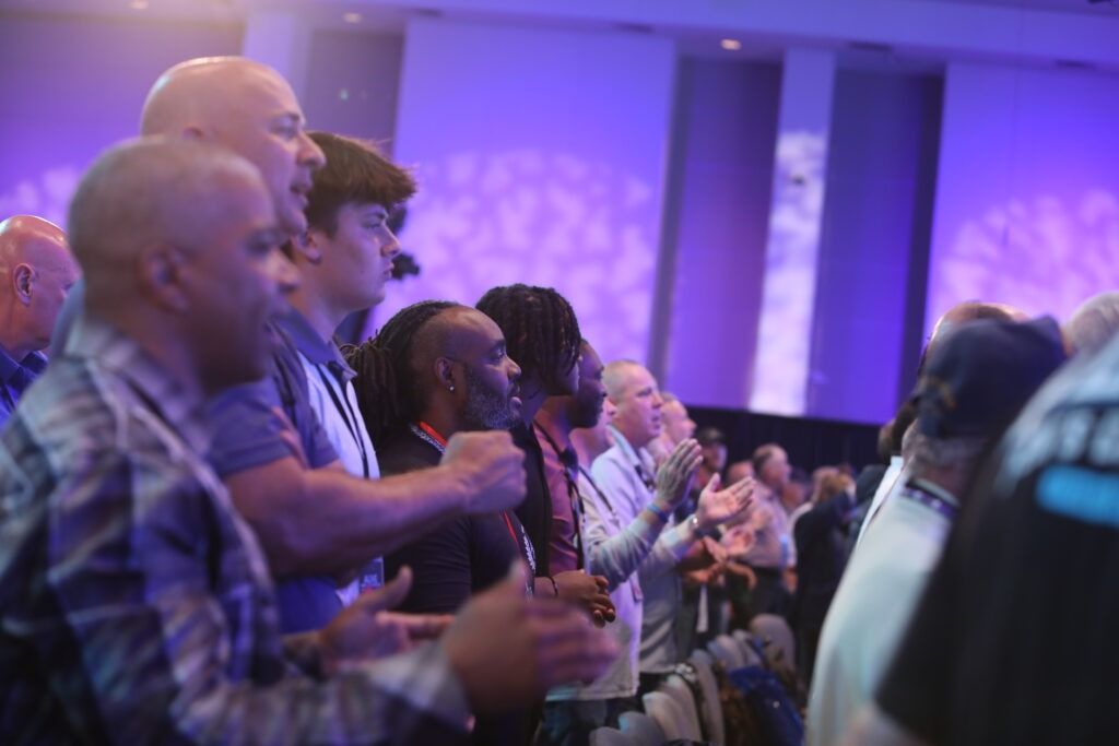 Audience clapping at a purple-lit event venue