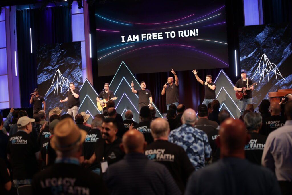 Stage with people worshiping under a screen reading “I AM FREE TO RUN!”