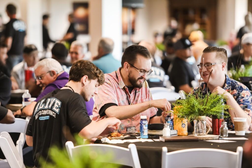 People seated at a restaurant table, eating and chatting in a bright indoor setting.