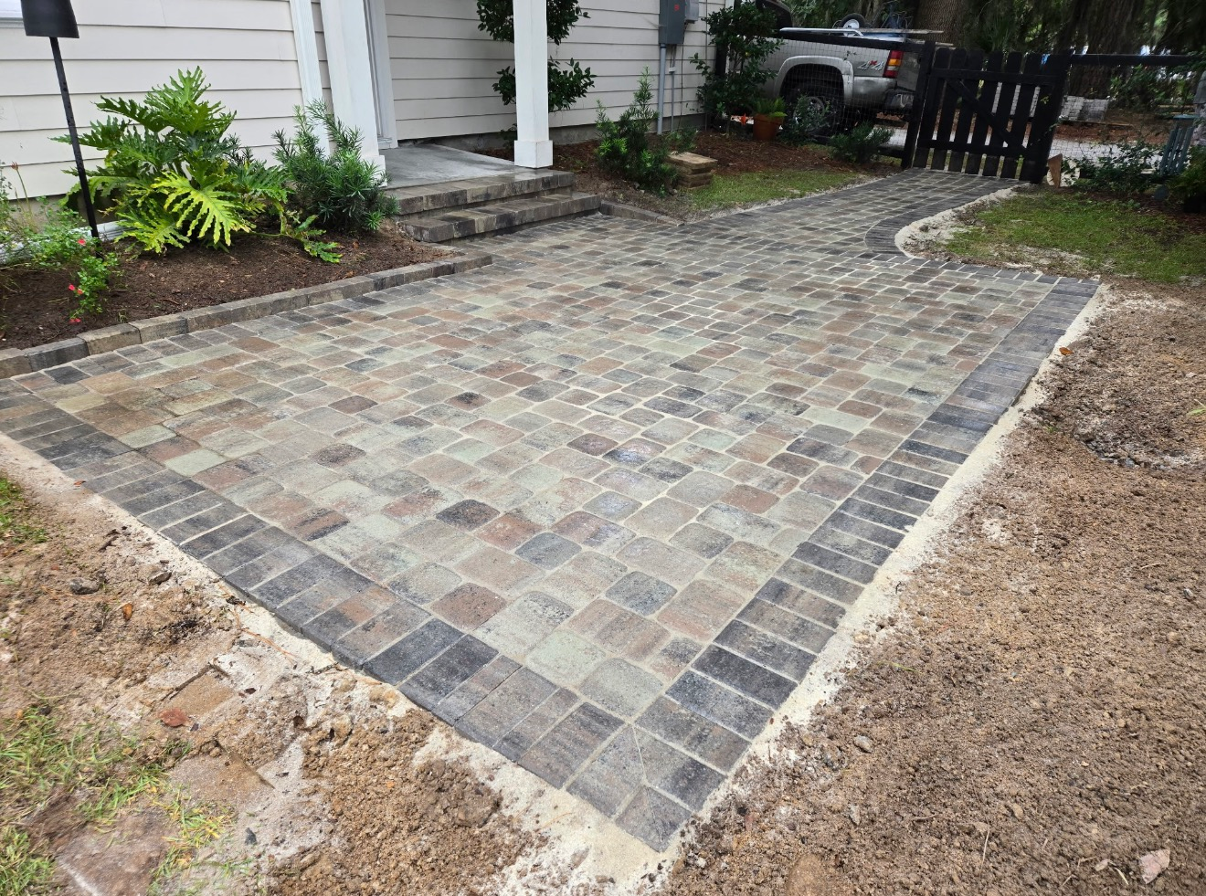A newly installed stone paver patio and walkway leading to the front steps of a house.