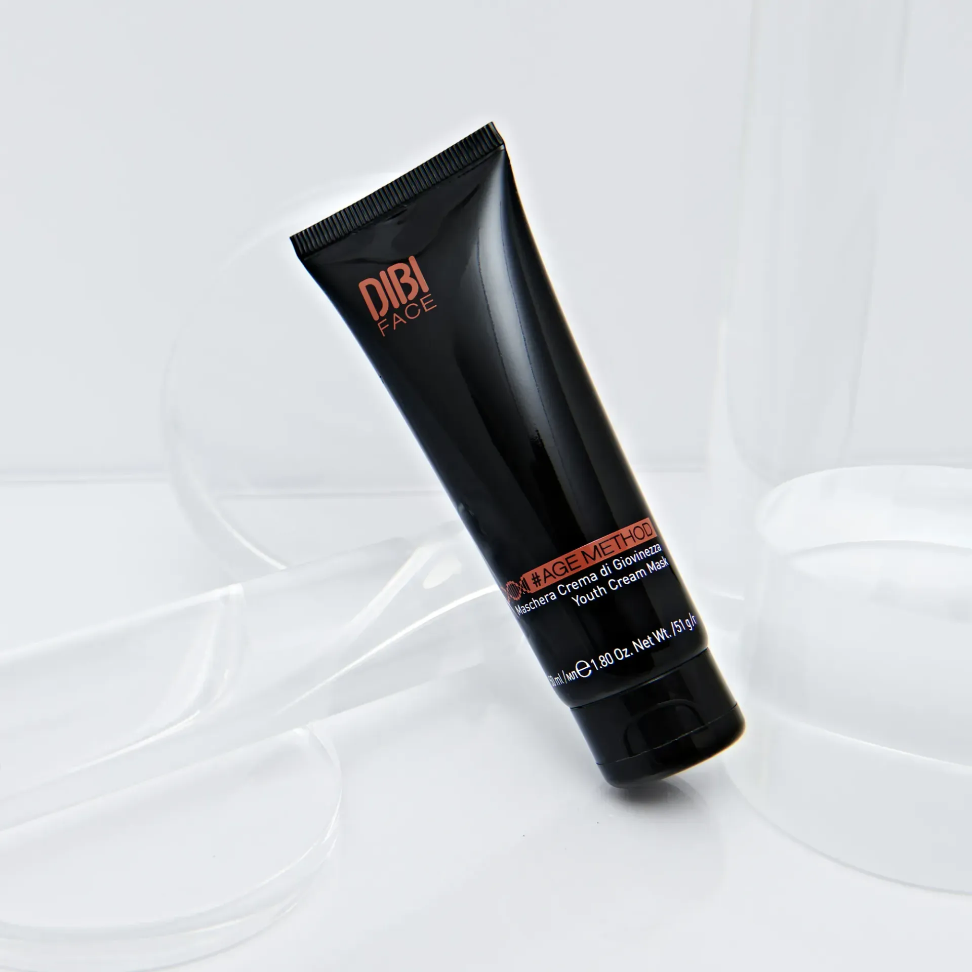 Tubetto di crema OBI PURE nero su sfondo bianco, appoggiato a una struttura in vetro.