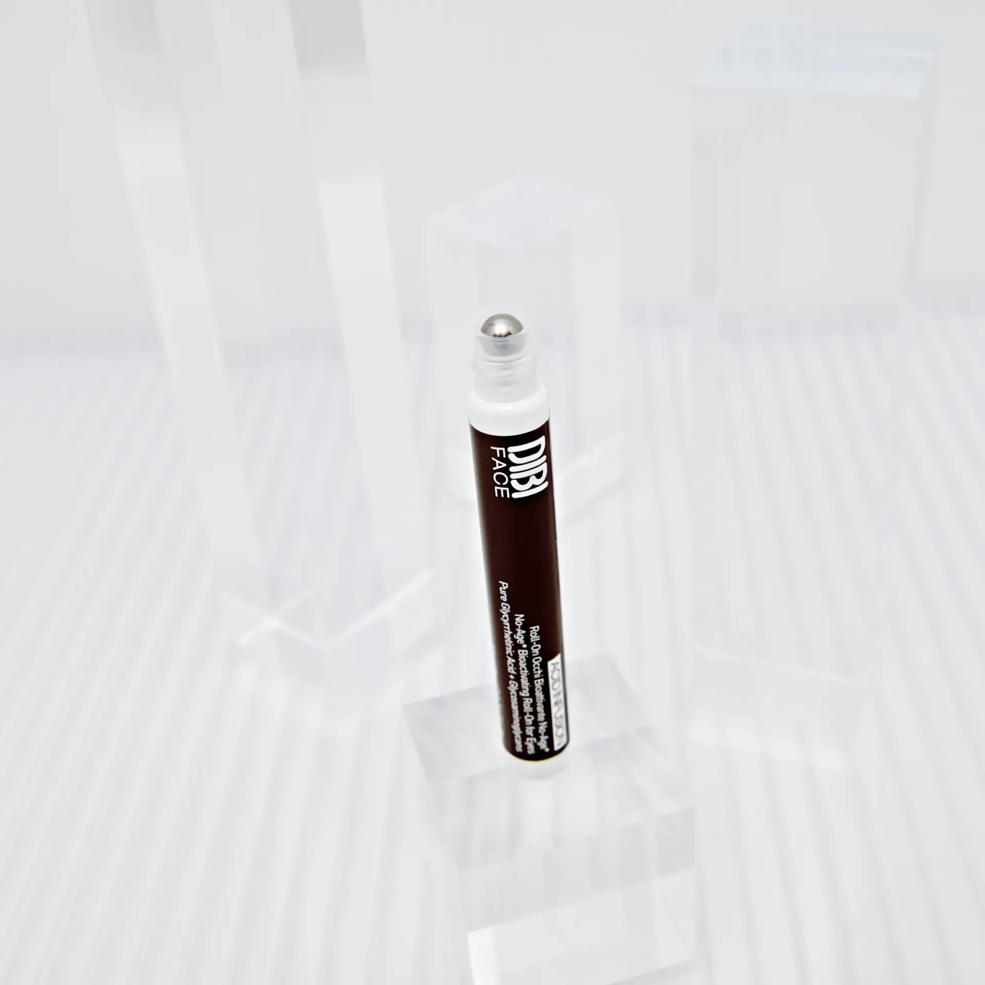 Applicatore cosmetico roll-on marrone con sfera argentata, su blocchi acrilici.