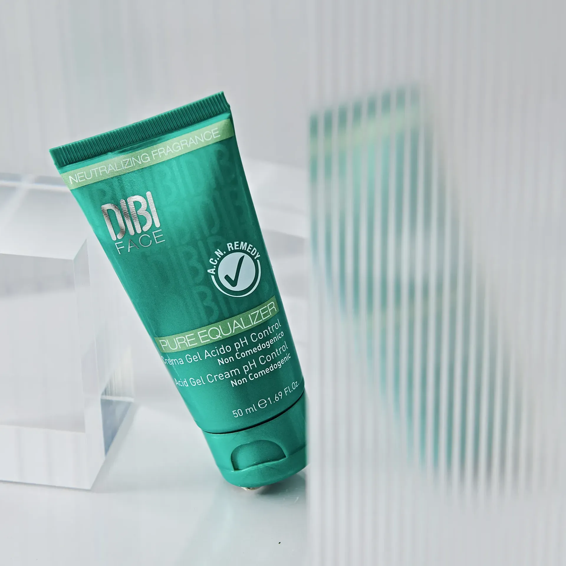 Tubetto cosmetico verde appoggiato su una superficie di vetro testurizzato. Etichetta