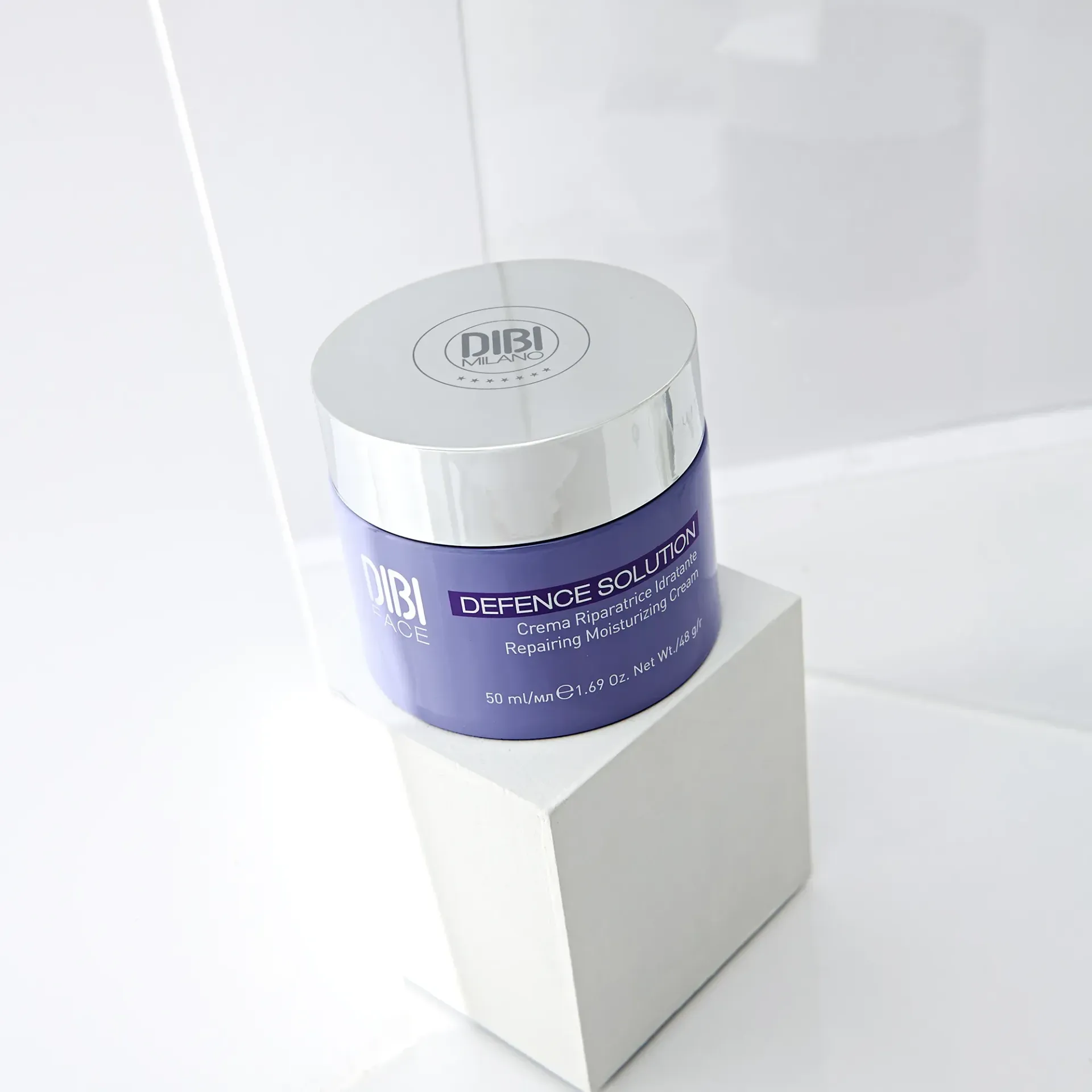 Barattolo viola di crema Dibi Defense Solutions, coperchio argentato, esposto su blocco bianco.