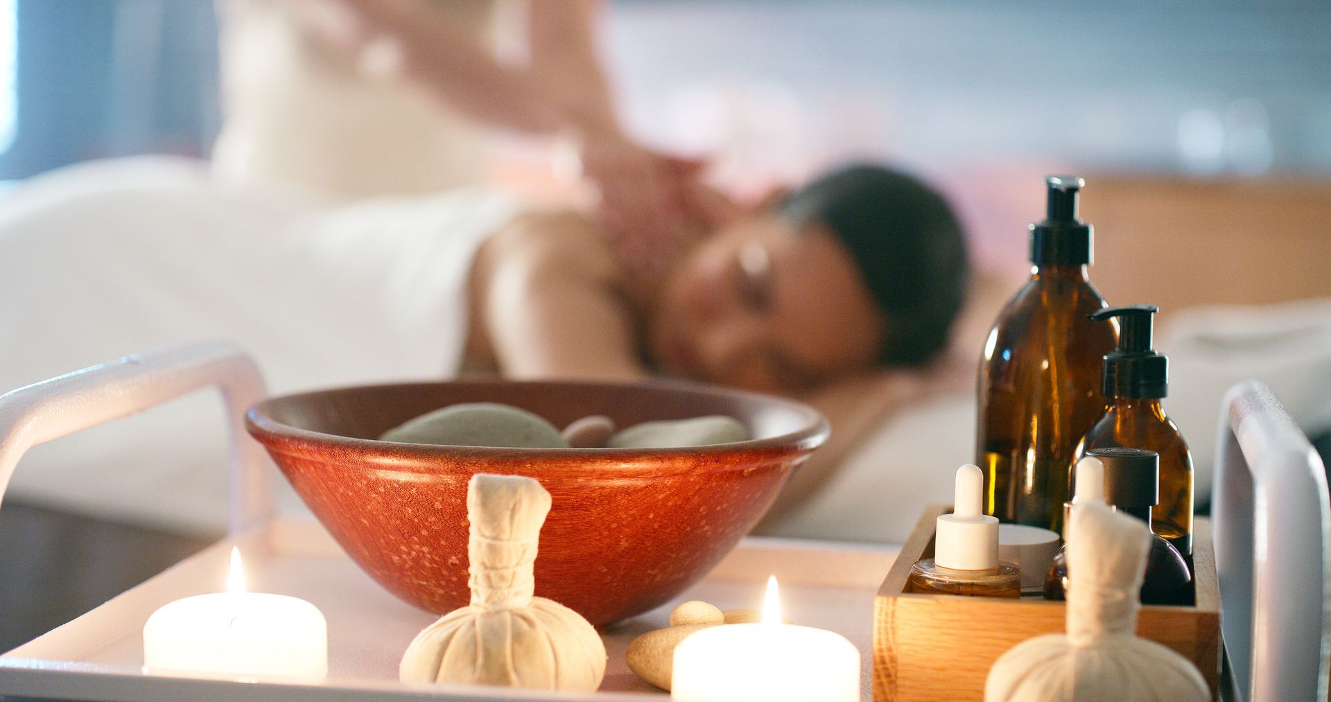 Ambiente spa con massaggio in corso, candele e oli essenziali.