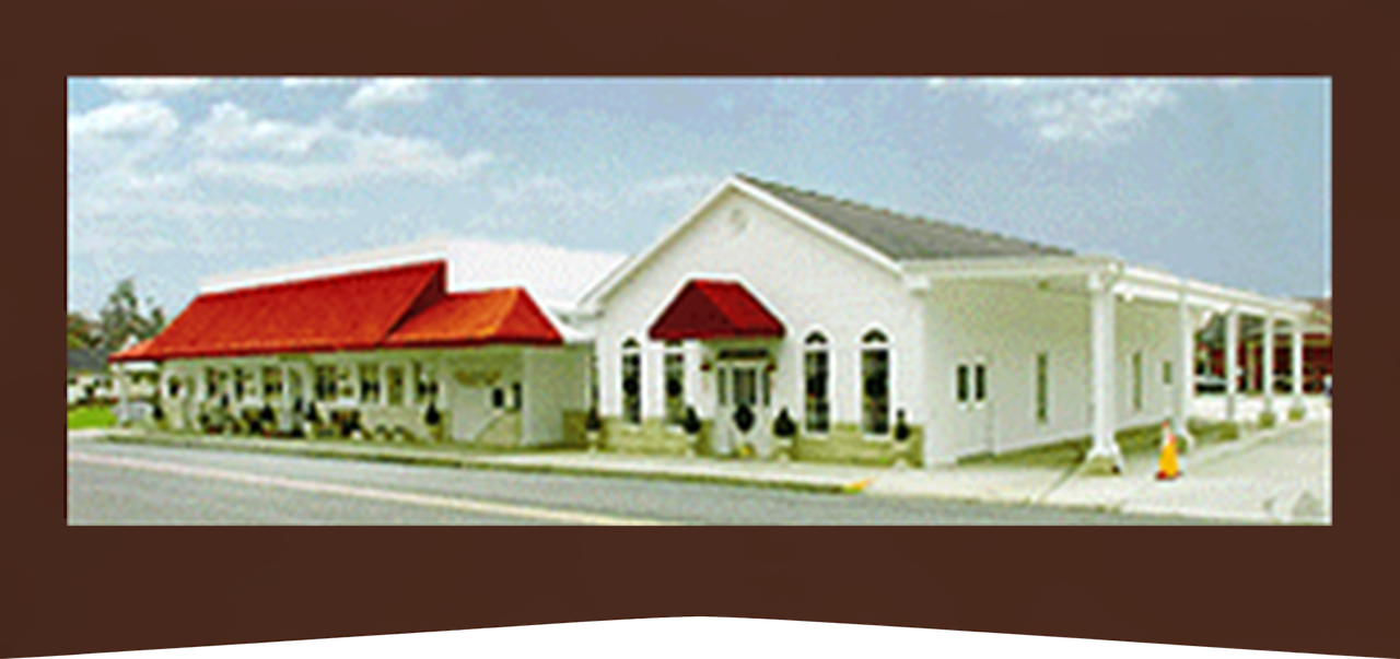 White building with red awnings and roof in a parking lot under a blue sky