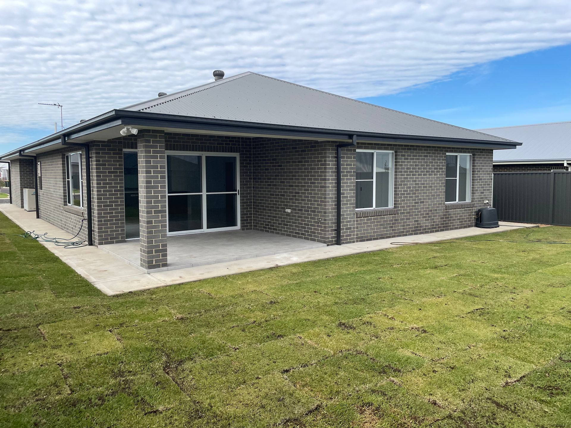 A brick house with a large lawn in front of it.