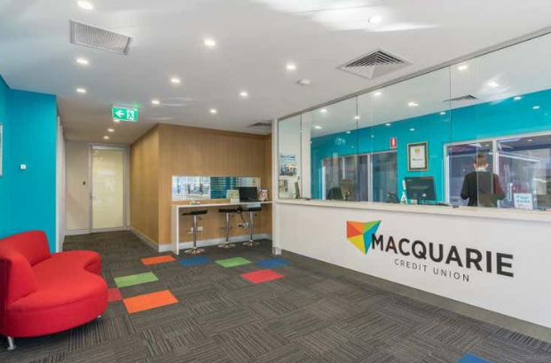 Macquarie Credit Union branch interior with red seating, reception desk, and teal walls.