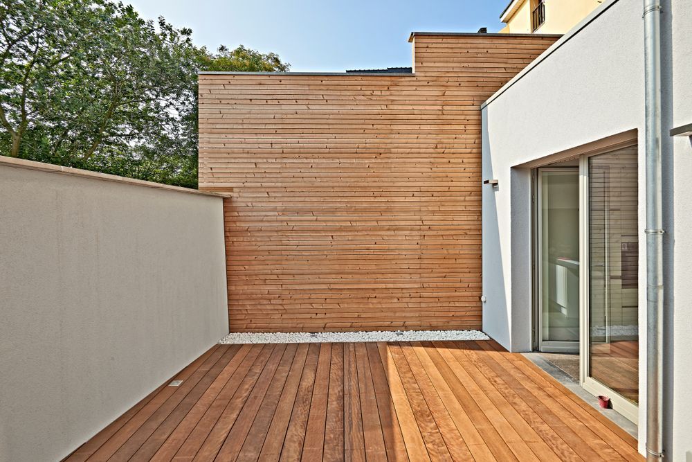 A wooden deck in front of a house with a wooden wall