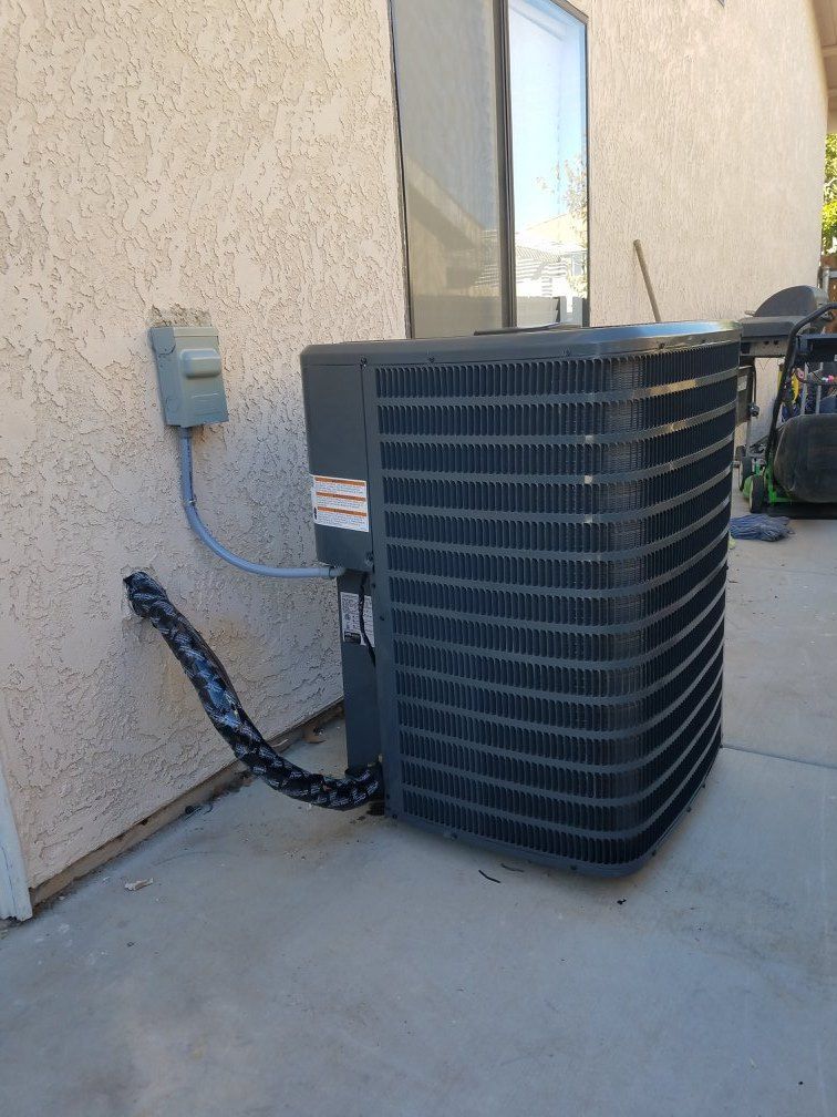 AC unit next to a beige wall, with a grey electrical box and black insulation.