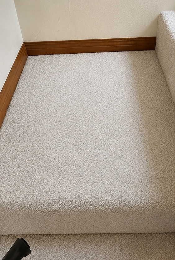 Carpeted stair landing with brown wood trim and a white textured wall.