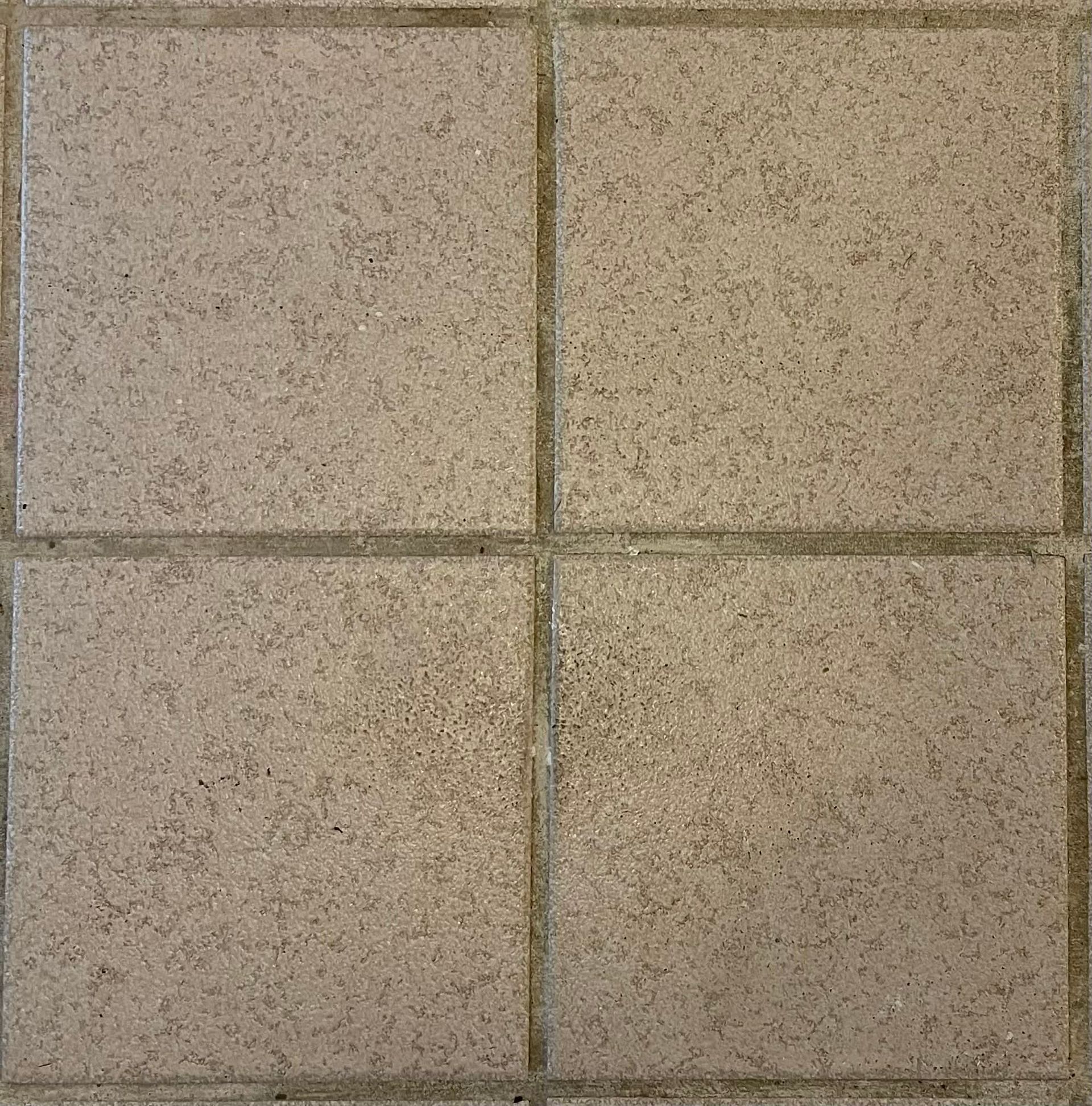 Four square beige concrete tiles with dark grout lines forming a 2x2 grid.