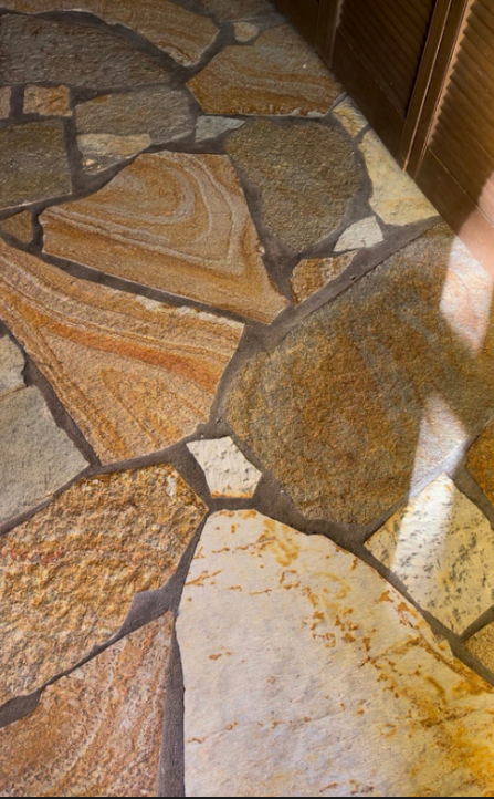Stone-tile floor with tan, brown, and white irregular paving pieces in sunlight