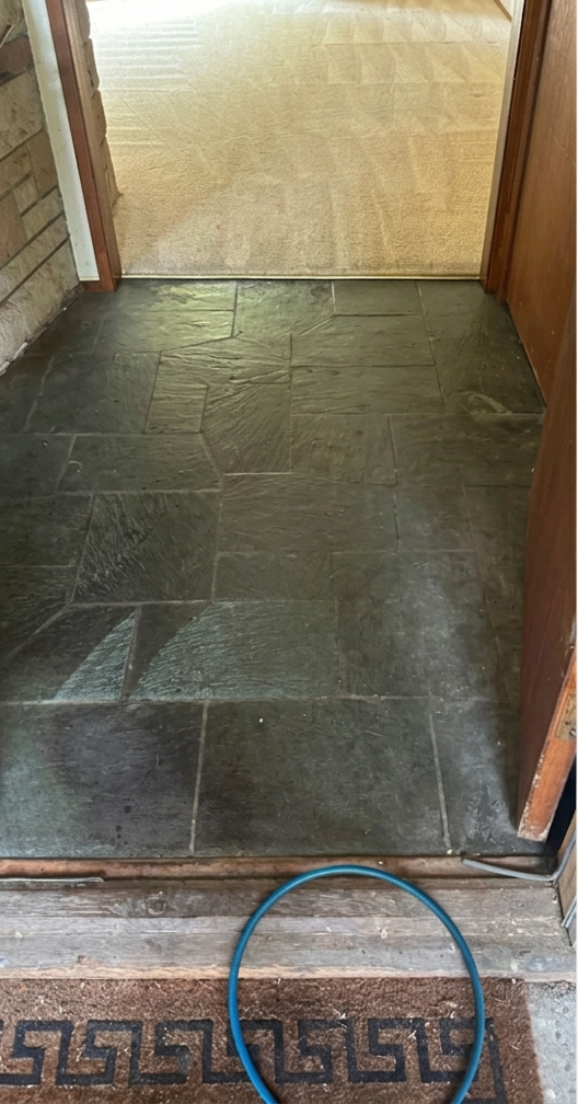 Dark stone-tile doorway threshold with a blue cable on the floor and patterned tile edging.