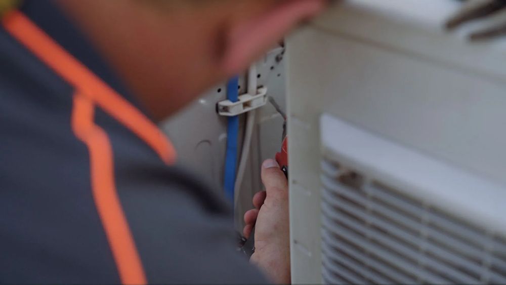 A Man Is Working On An Air Conditioner With A Pair Of Pliers — Entire Trades in Port Stephens, NSW