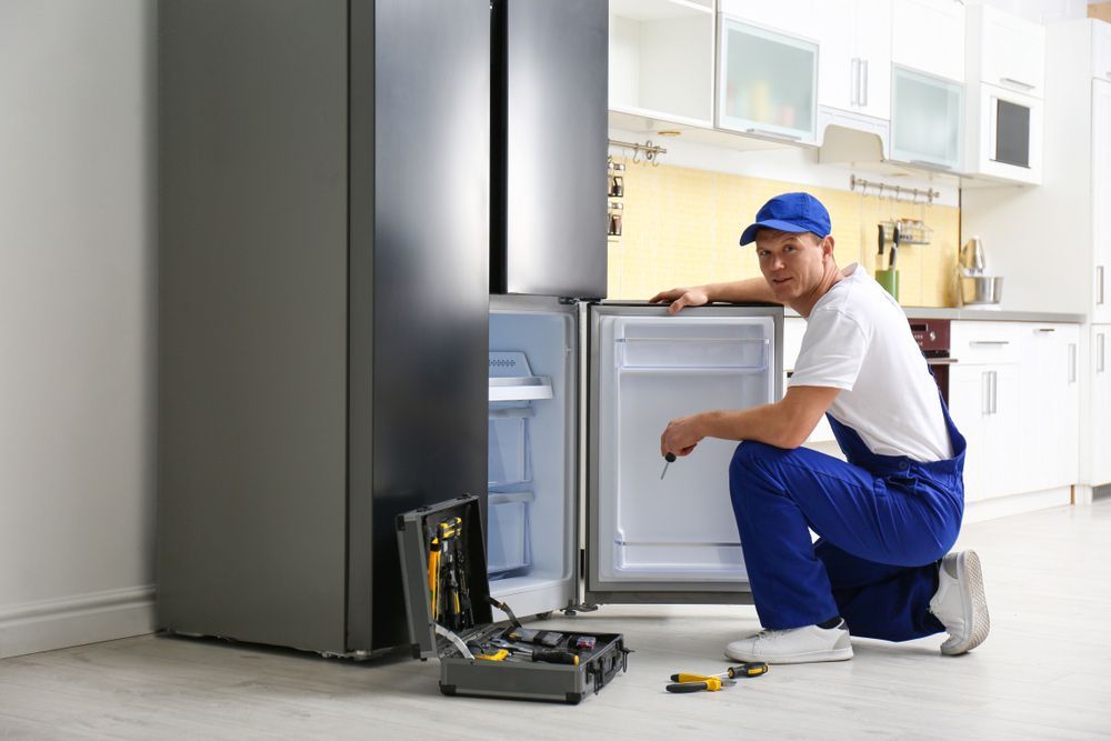 Male Technician With Screwdriver Repairing Refrigerator — Entire Trades in Central Coast, NSW