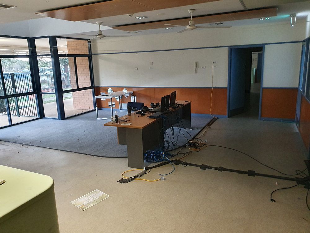 A Large Room With A Desk And Two Computers In It Before Renovation The Office Room — Entire Trades in Port Stephens, NSW
