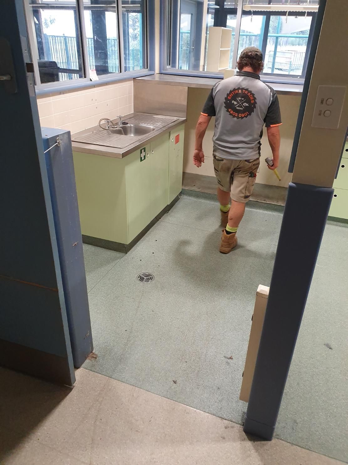 A Man Is Walking Through a Kitchen with A Sink — Entire Trades in Singleton, NSW