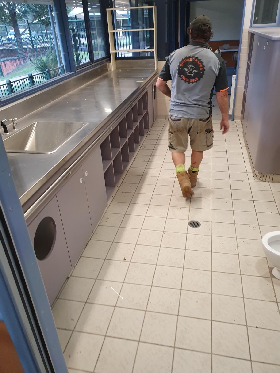 A Man Is Walking Down a Tiled Floor in A Bathroom — Entire Trades in Singleton, NSW