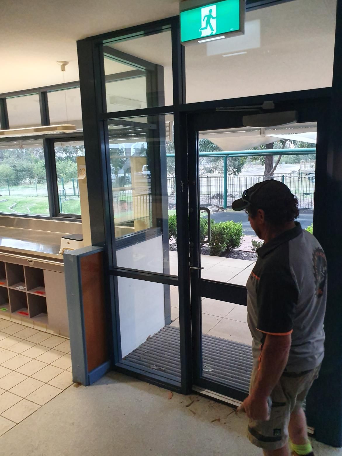 A Man Is Standing in Front of A Glass Door in A Building — Entire Trades in Singleton, NSW