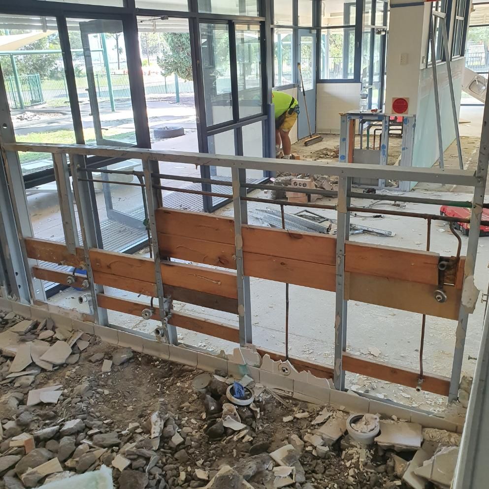 A Man Is Working on A Wall in A Building Under Construction — Entire Trades in Singleton, NSW