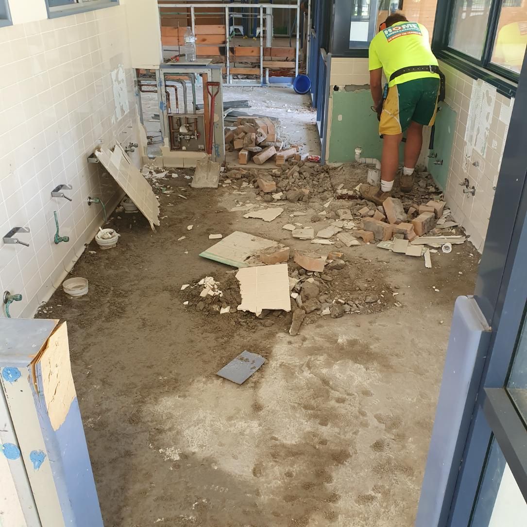 A Man in A Yellow Shirt and Green Shorts Is Standing in A Messy Room — Entire Trades in Singleton, NSW