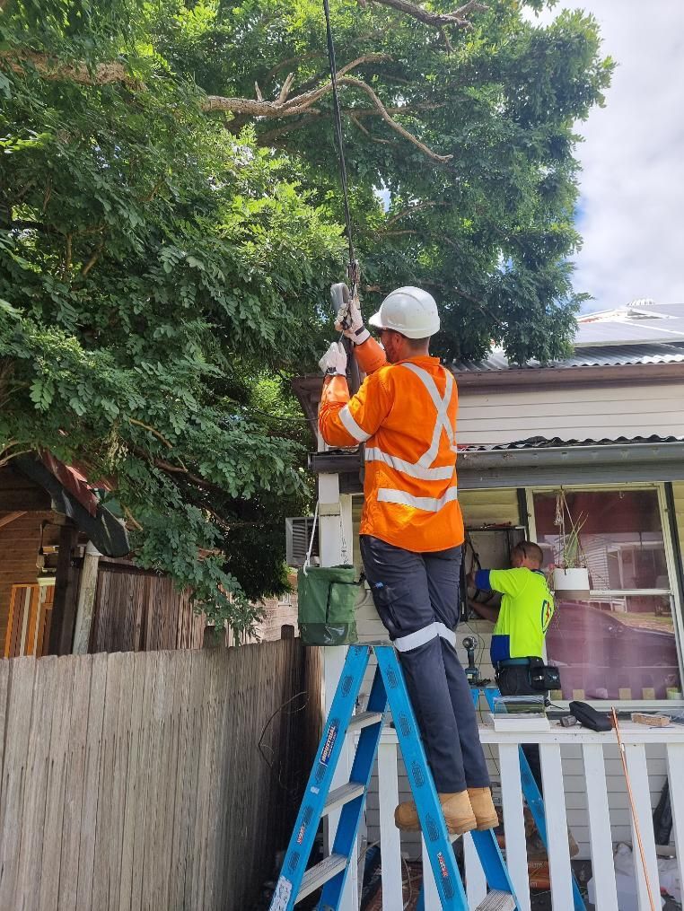 A Man Is Standing on A Ladder in Front of A House — Entire Trades in Maitland, NSW