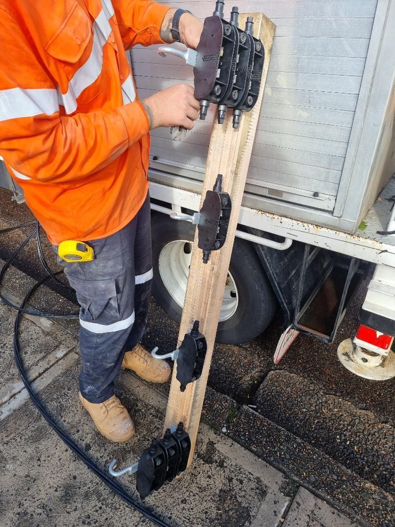 A Man in An Orange Shirt Is Working on A Piece of Wood Next to A Truck — Entire Trades in Maitland, NSW