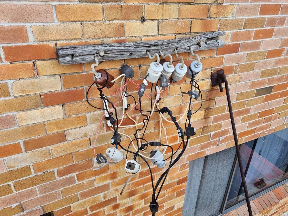 A Bunch Of Wires Are Hanging On A Brick Wall — Entire Trades in Maitland, NSW