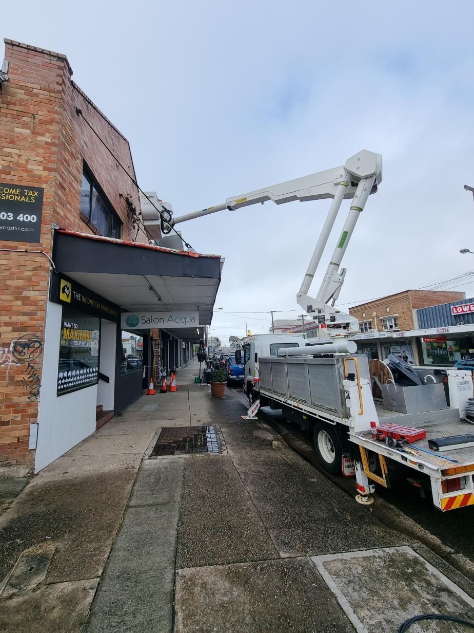A Crane Is Sitting on The Side of The Road in Front of A Building — Entire Trades in Maitland, NSW