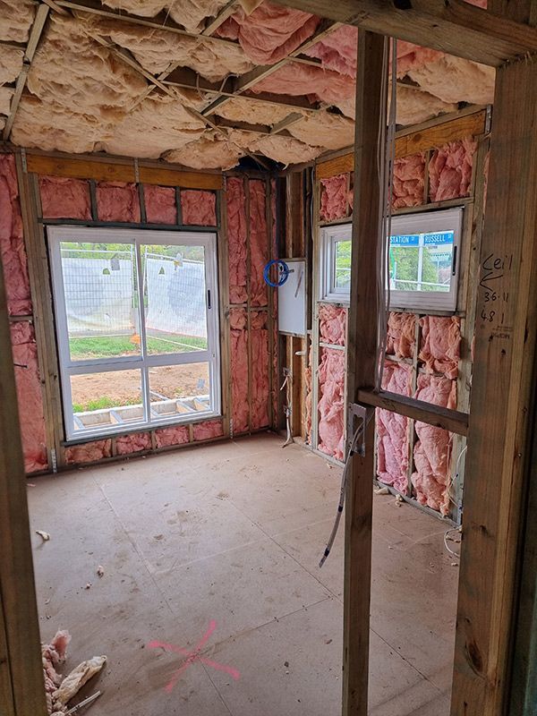 An Interior View Of A Room Featuring Pink Insulation And A Window Of A House Under Construction — Entire Trades in Cessnock, NSW