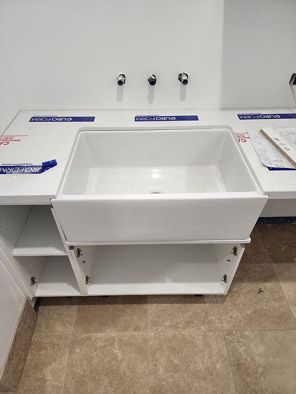 A White Bathroom Sink With A White Cabinet In A Bathroom With Two Showers And A Toilet — Entire Trades in Singleton, NSW
