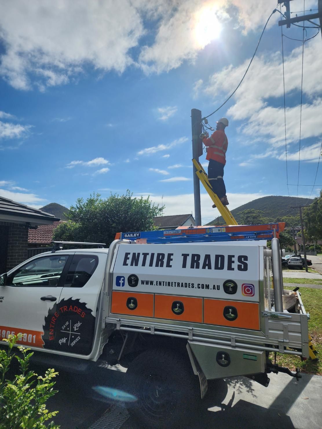 A Man Is Standing on A Ladder on Top of A Truck that Says Entire Trades — Entire Trades in Maitland, NSW