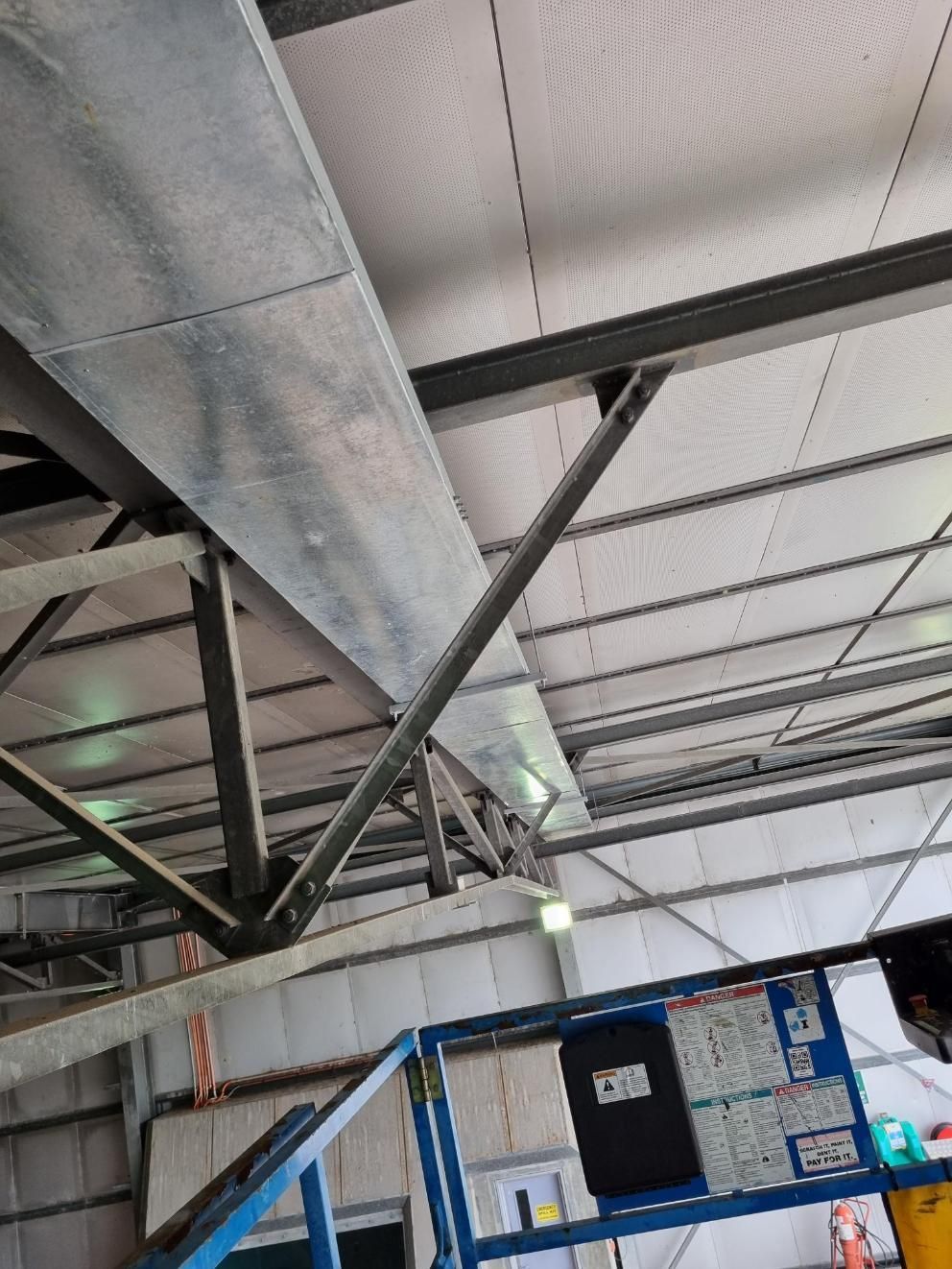 A Large Metal Pipe Is Hanging from The Ceiling of A Building — Entire Trades in Maitland, NSW