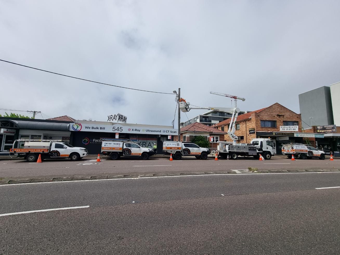 A Row of Trucks Are Parked on The Side of The Road in Front of A Building — Entire Trades in Maitland, NSW