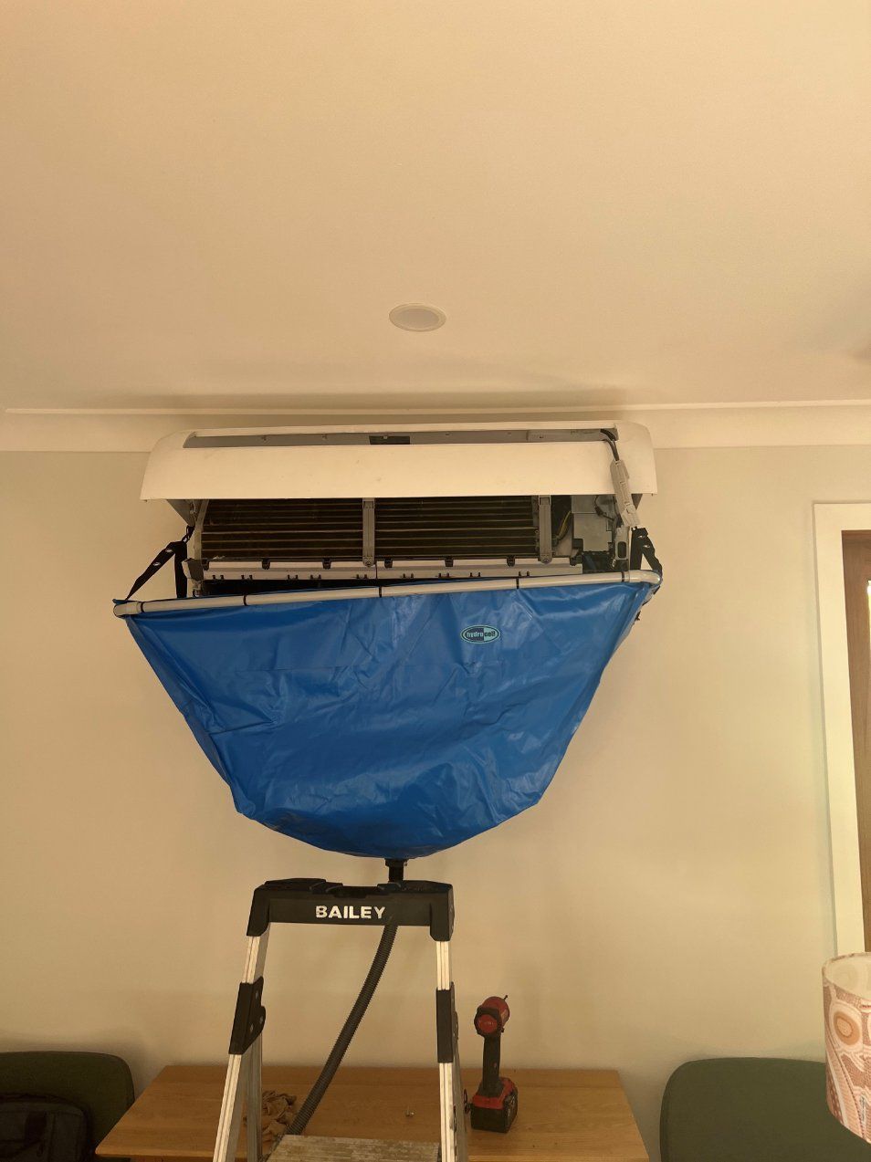 A Blue Bag Is Hanging from The Ceiling of An Air Conditioner — Entire Trades in Maitland, NSW