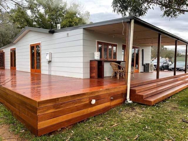 A White House With A Large Wooden Deck Complete Renovation — Entire Trades in Maitland, NSW