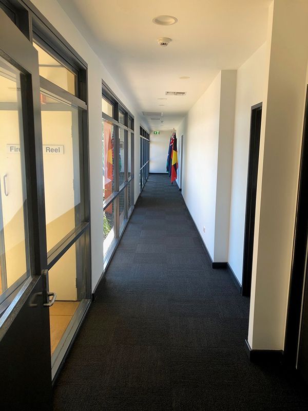 A Long Hallway With Black Carpet And Windows — Entire Trades in Port Stephens, NSW