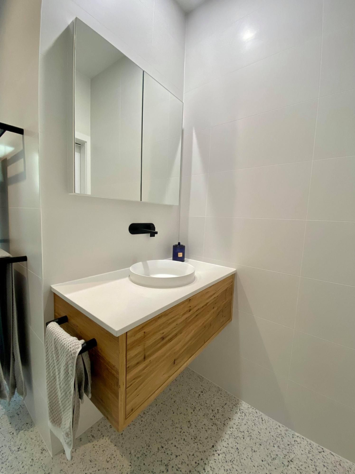 A Bathroom with A Sink, Mirror and Towel Rack — Entire Trades in Maitland, NSW