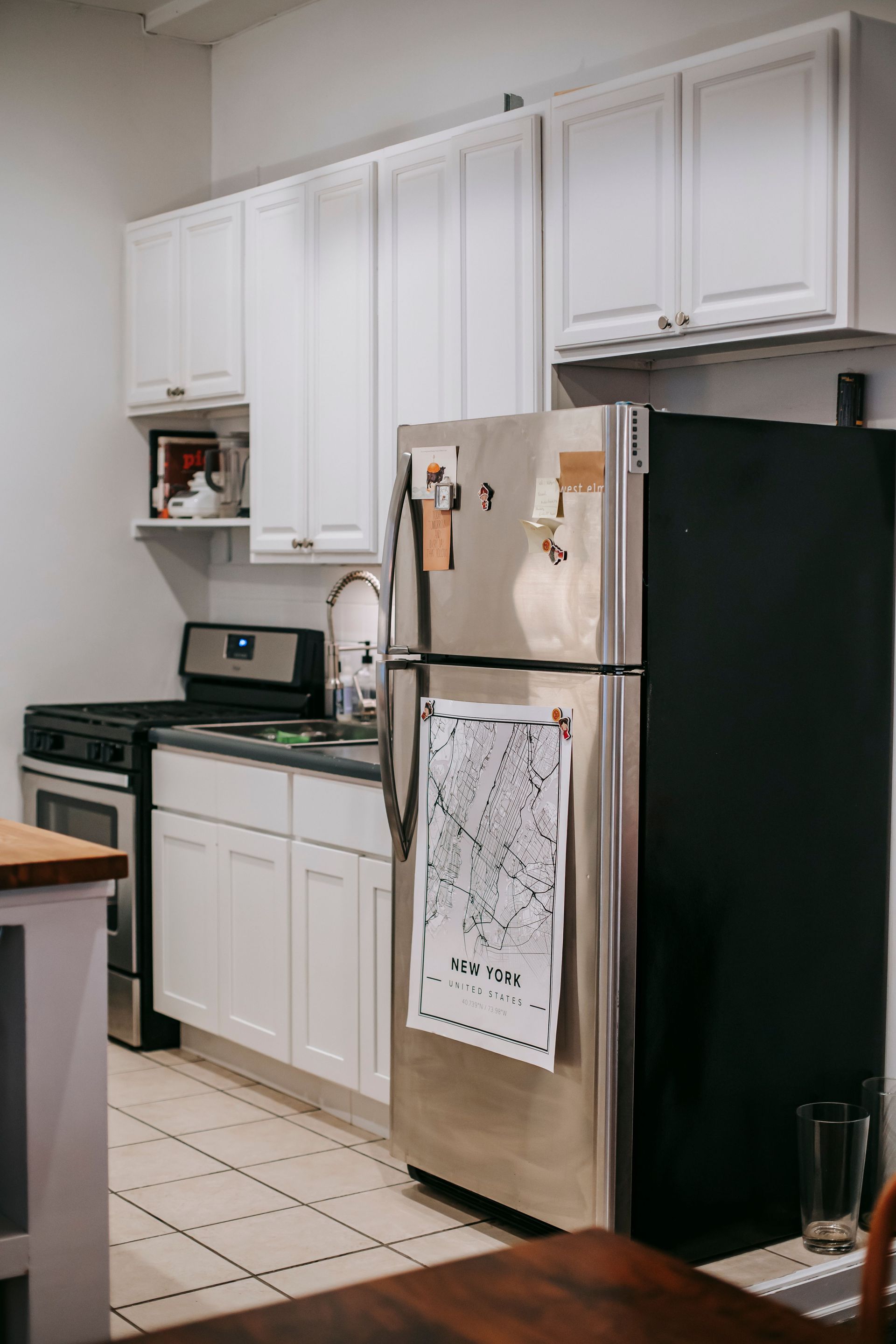 White kitchen with cabinets, refrigerator, stove, and tiled floor