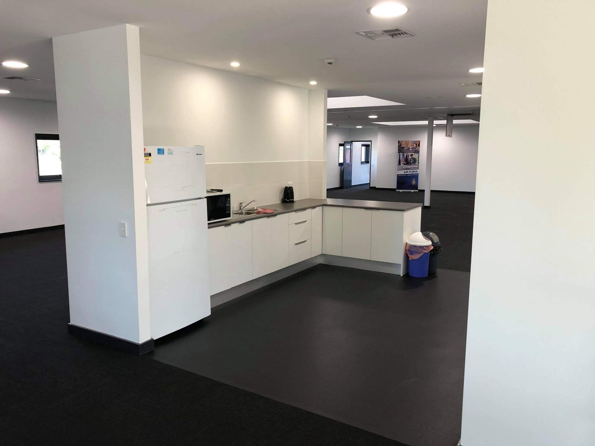 An Empty Kitchen with White Cabinets and A Refrigerator — Entire Trades in Maitland, NSW