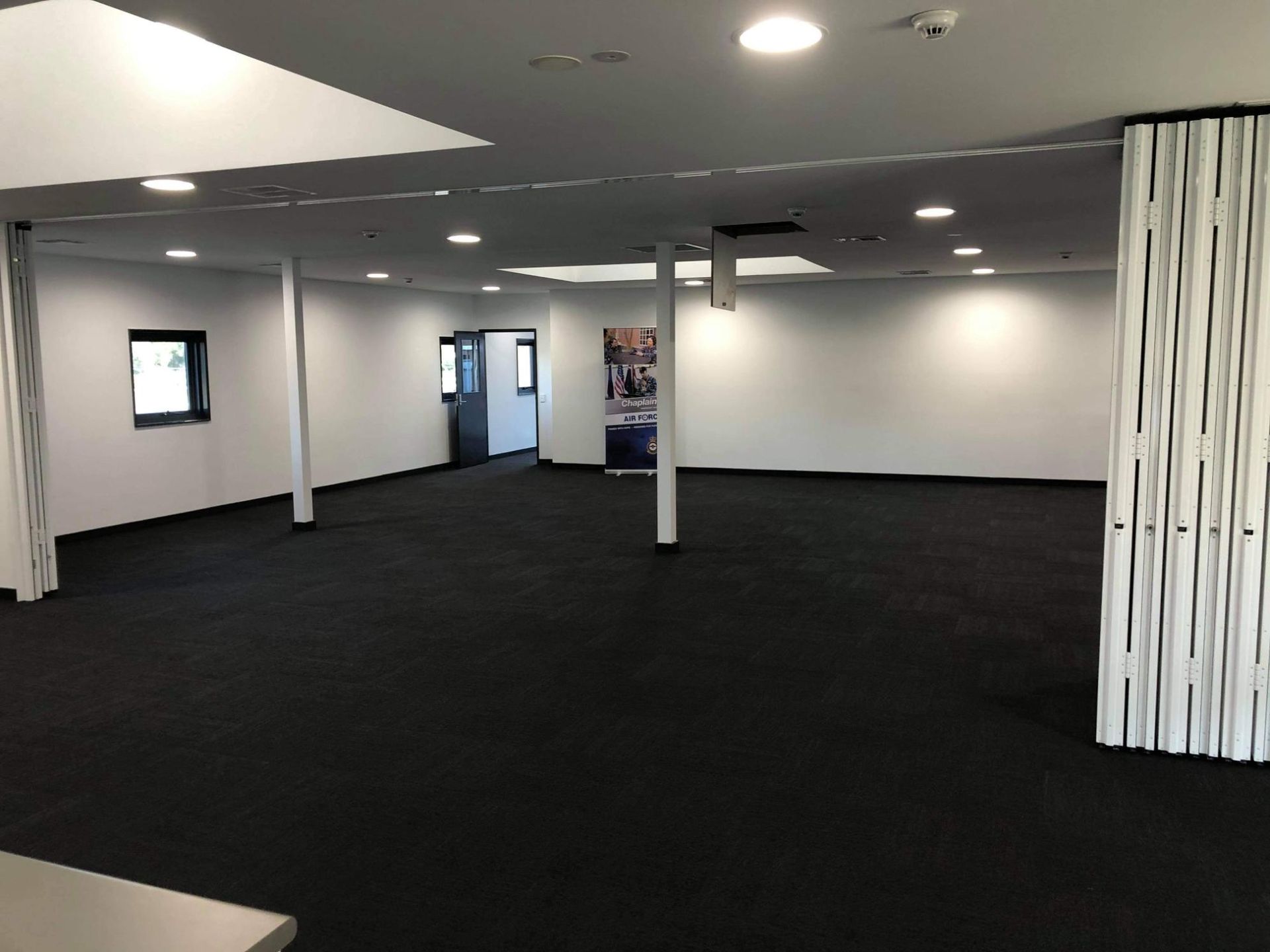 A Large Empty Room with Black Carpet and White Walls — Entire Trades in Maitland, NSW