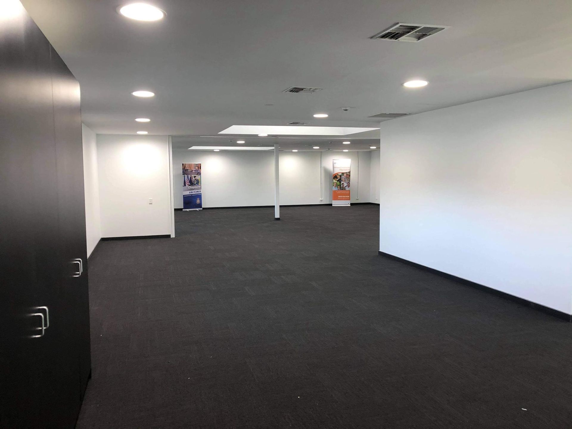 A Large Empty Room with A Black Carpet and White Walls — Entire Trades in Maitland, NSW