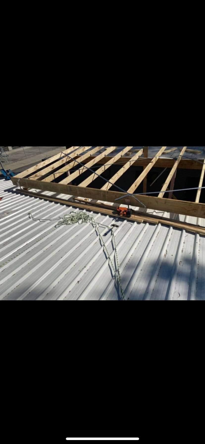 A White Metal Roof with Wooden Beams Being Built on Top of It — Entire Trades in Maitland, NSW
